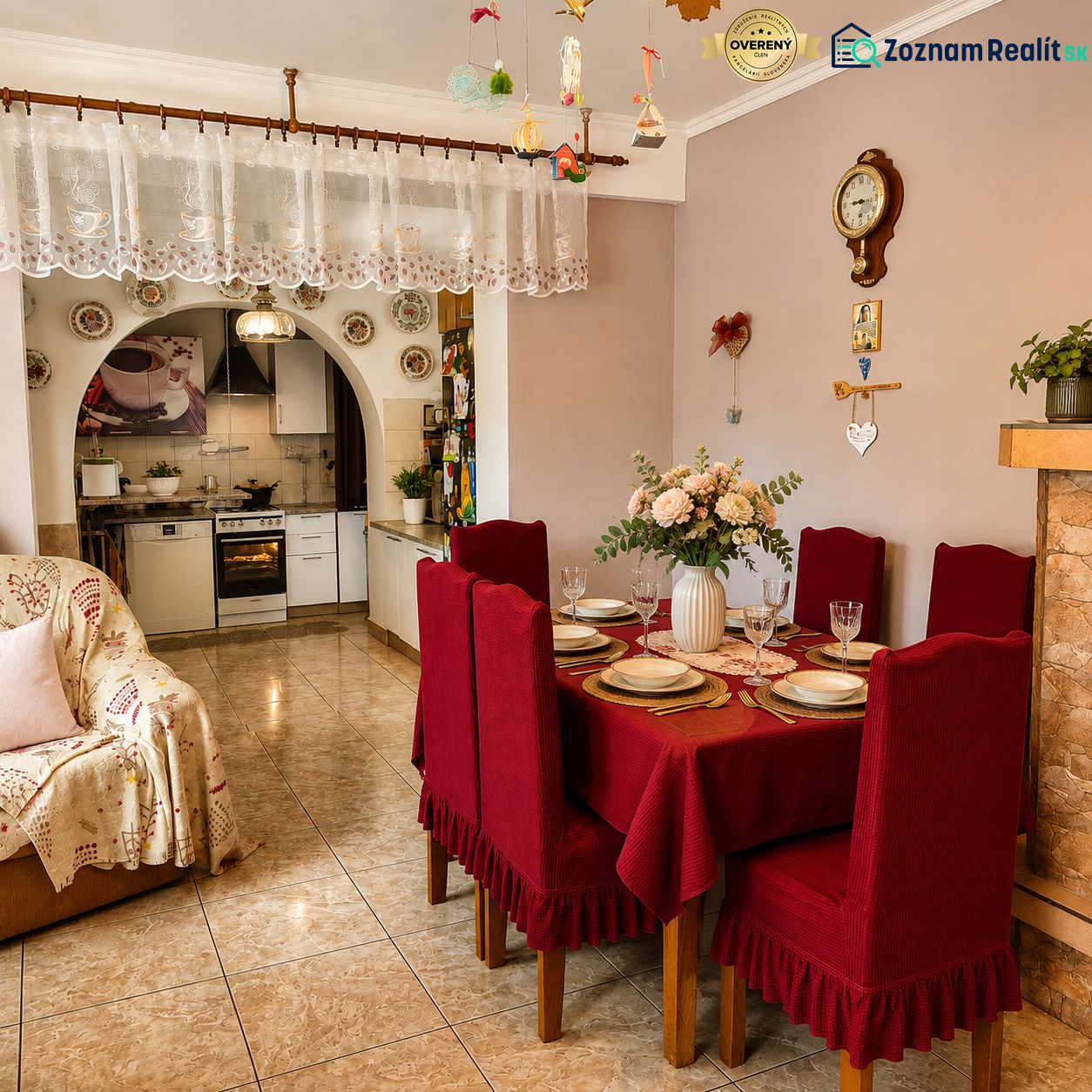 Esszimmer in einem Einfamilienhaus mit roter Tischdecke, Küche und Dekoration mit einer antiken Wanduhr.