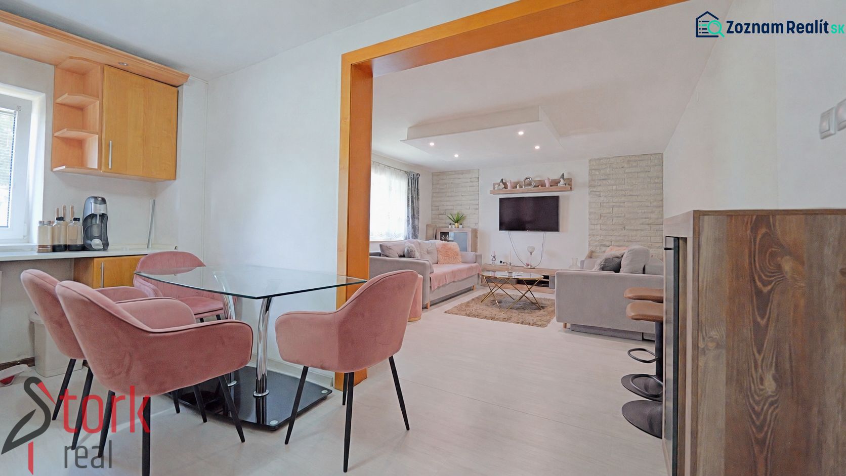 Innenraum eines Einfamilienhauses mit rosa Stühlen, Glastisch und Wohnzimmer mit Sofa.