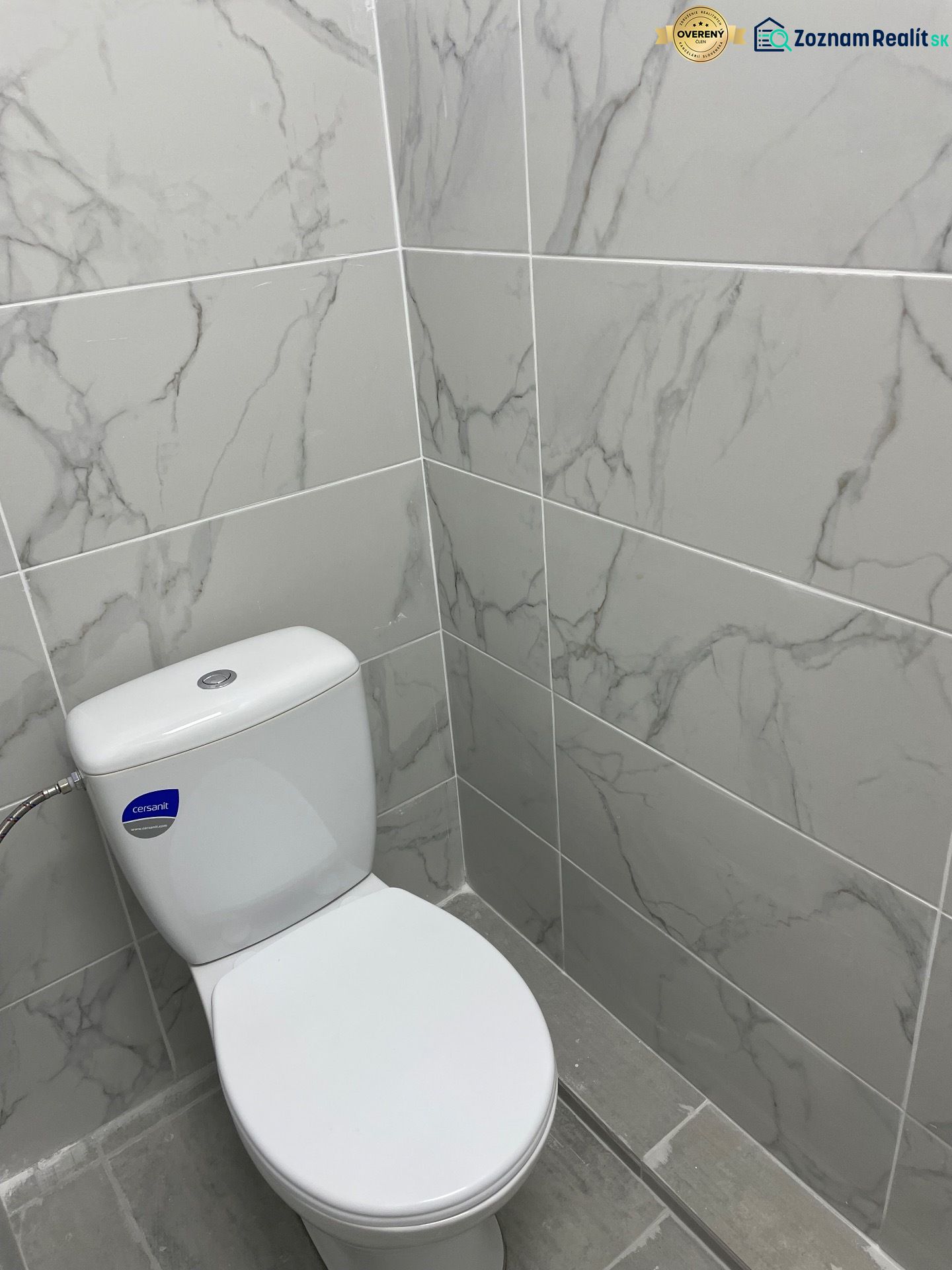 Toilette mit Marmorverkleidung in Geschäftsräumen, grauer Boden.