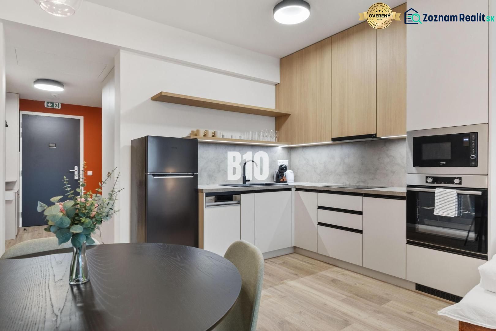 Küche mit Esstisch, Geräten und Holzboden in einer Einzimmerwohnung.