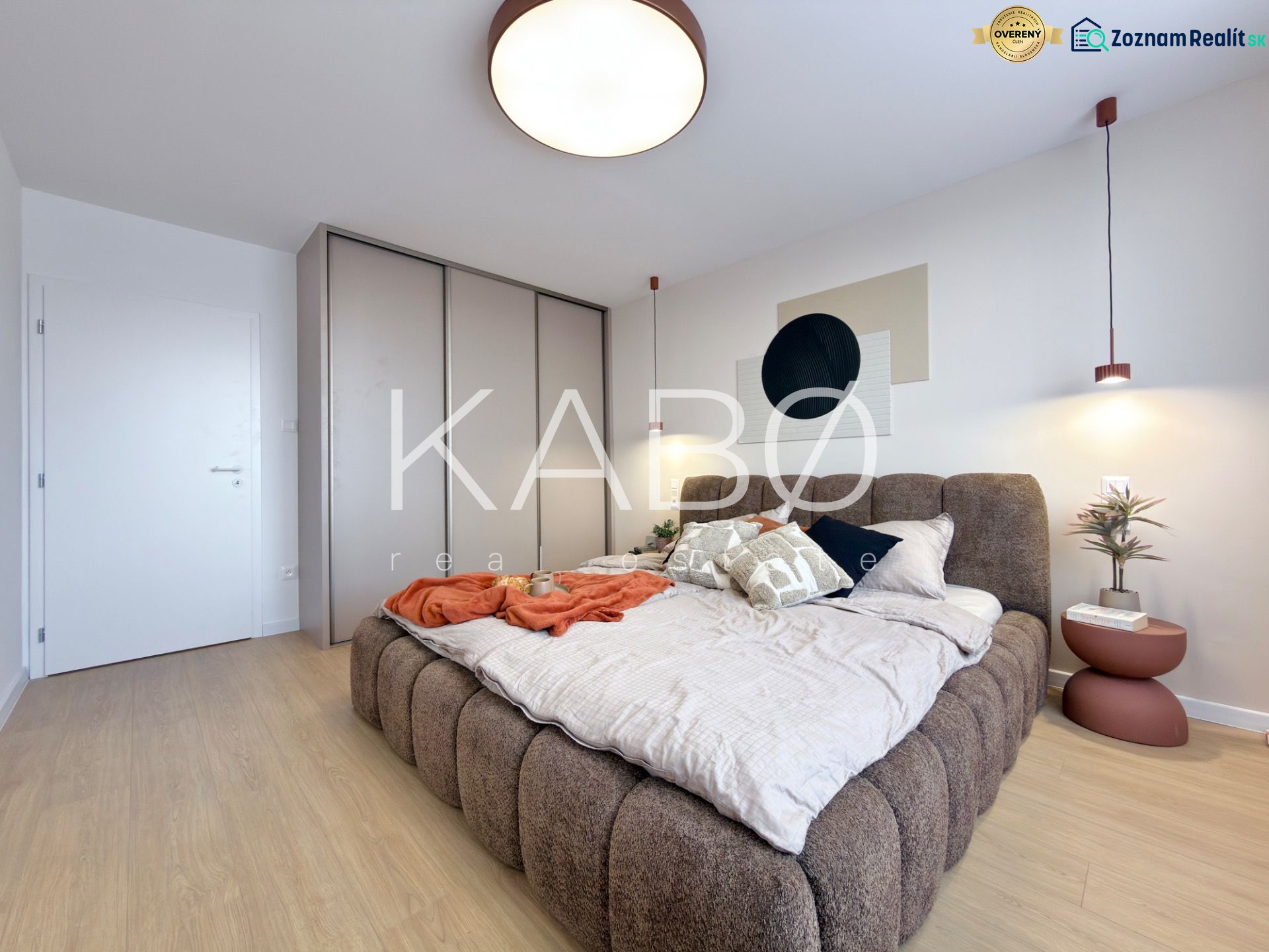 Schlafzimmer in einer 3-Zimmer-Wohnung mit einem großen Bett und einem Boden in Holzoptik.