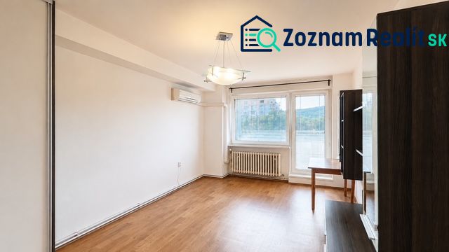Wohnzimmer mit Holzboden, Klimaanlage und großem Fenster in einer 3-Zimmer-Wohnung.