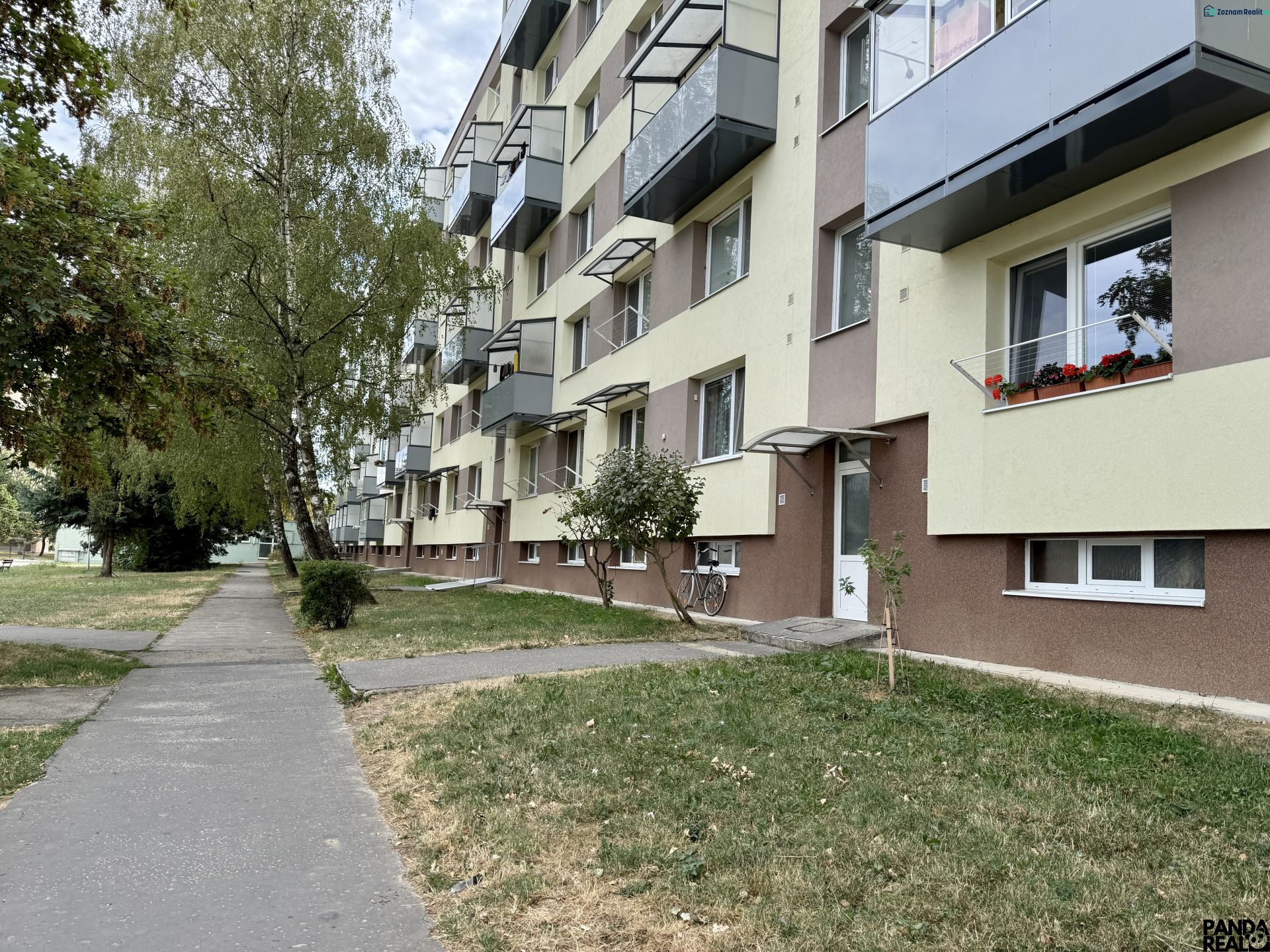 Ein Wohnhaus mit Grünflächen und einem Gehweg, gelegen in Topoľčany, umgeben von Bäumen.