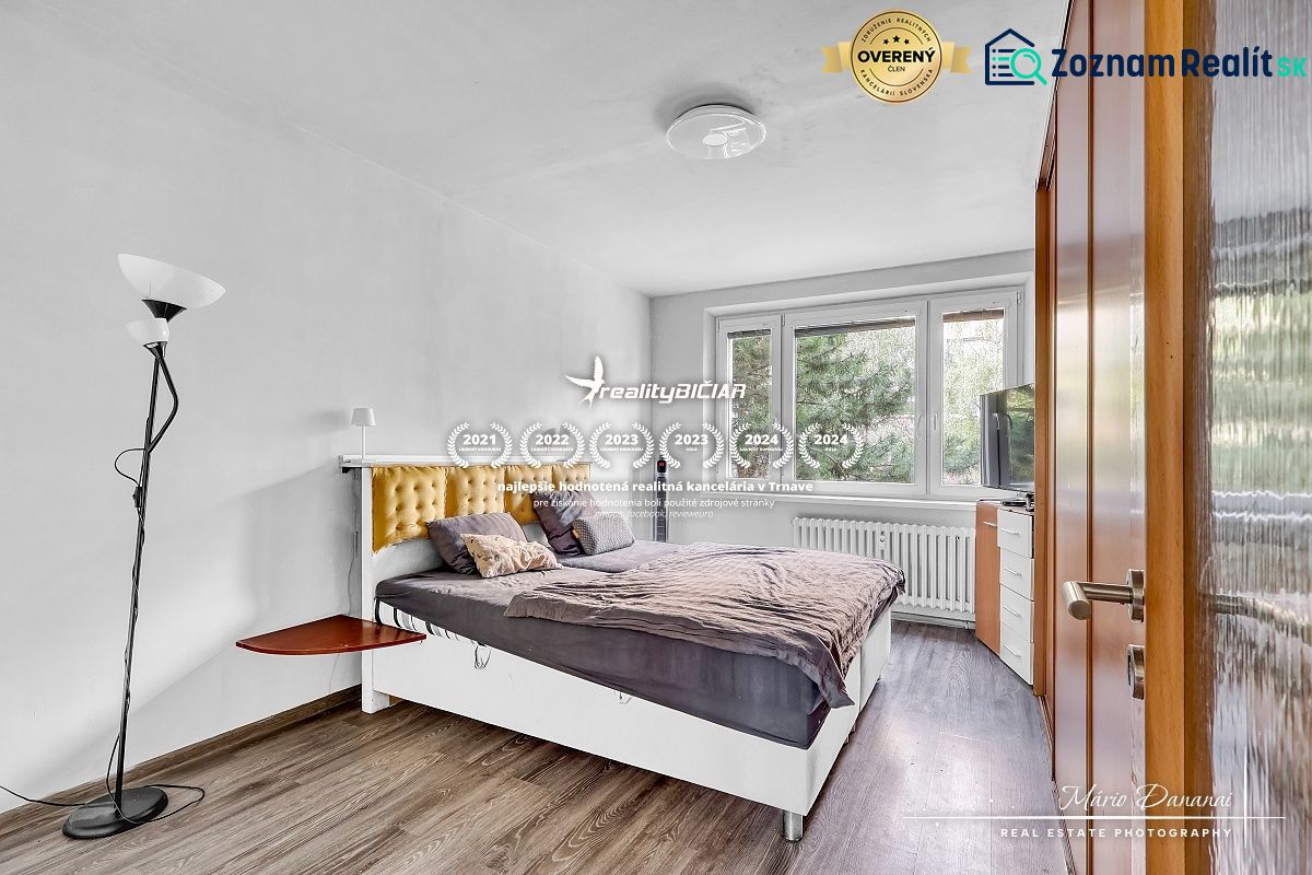 Schlafzimmer mit Bett und Holzboden in einer Zweizimmerwohnung.