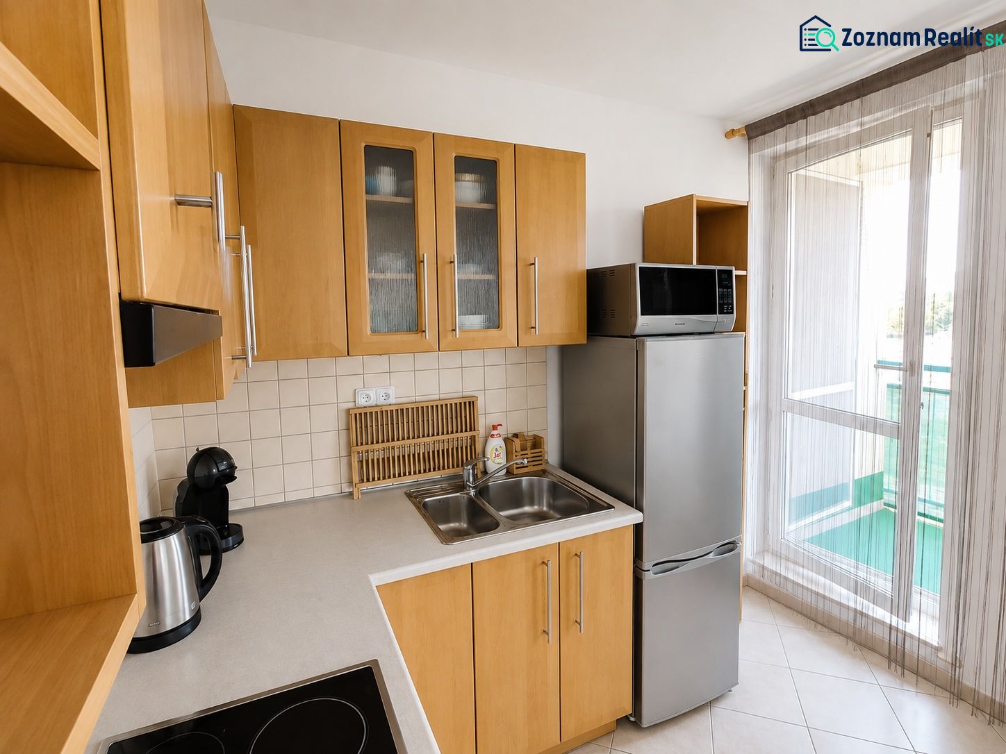 Küche mit Holzschränken, Kühlschrank und Mikrowelle in einer Zweizimmerwohnung.