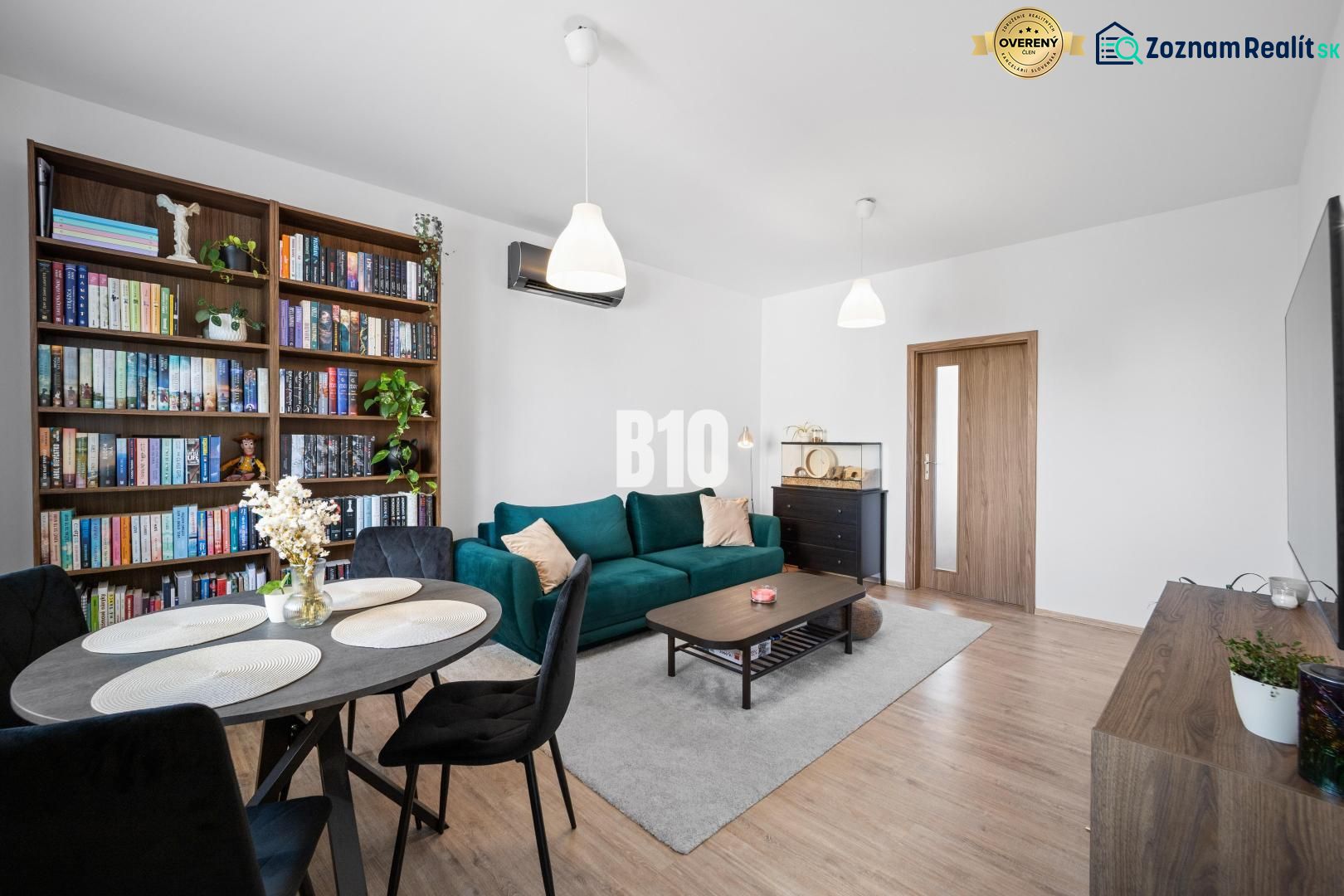 Wohnzimmer in einer Zweizimmerwohnung mit Holzdekorboden und Bücherregal.