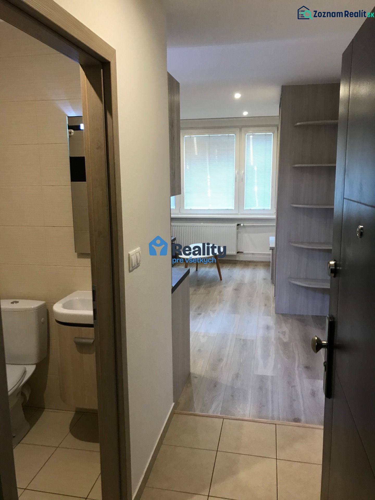 Ein Studio-Apartment mit Holzdekorboden, sichtbar ist das Badezimmer und der Wohnbereich.