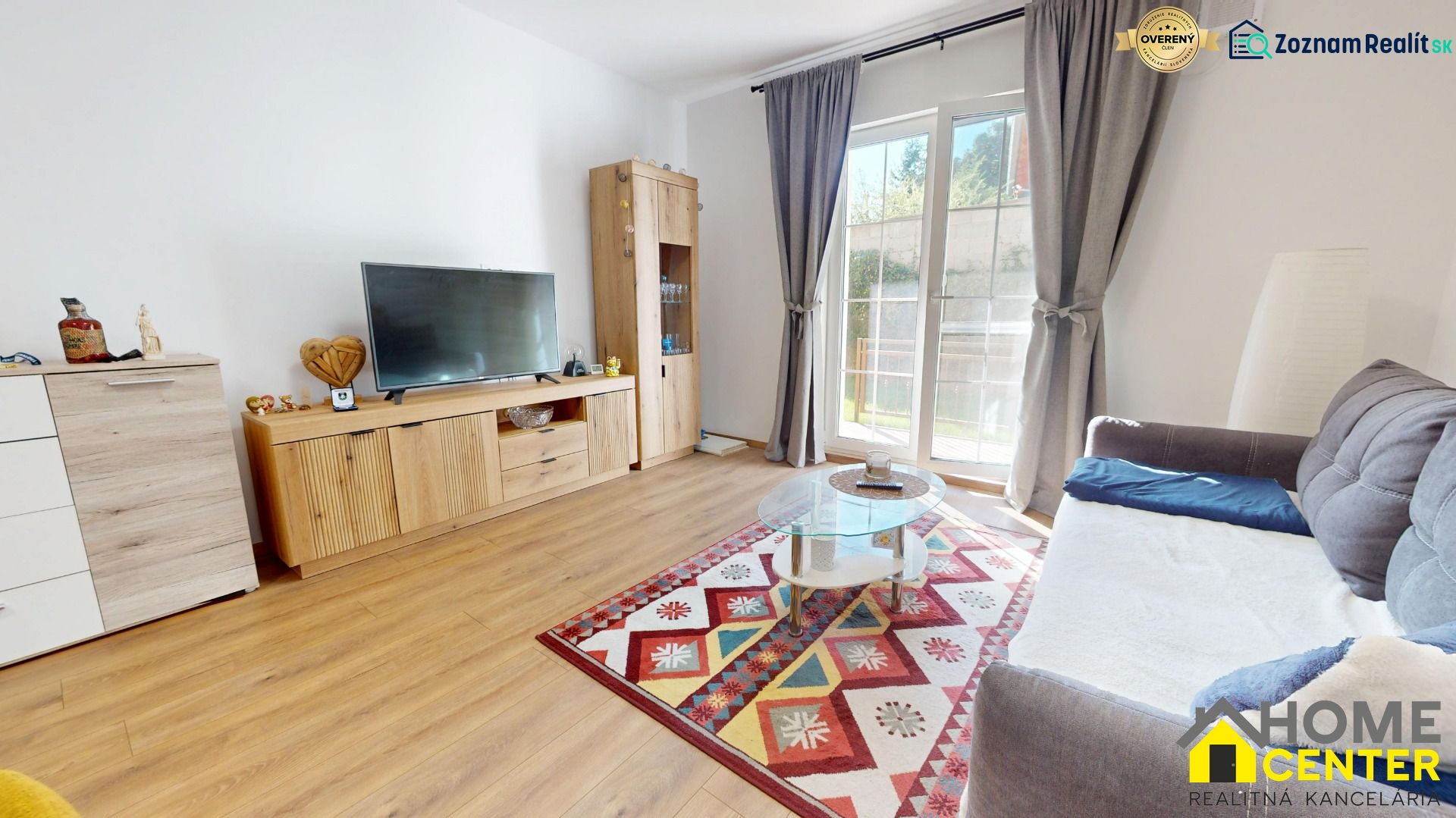 Wohnzimmer in einer 2-Zimmer-Wohnung mit Holzboden und buntem Teppich.