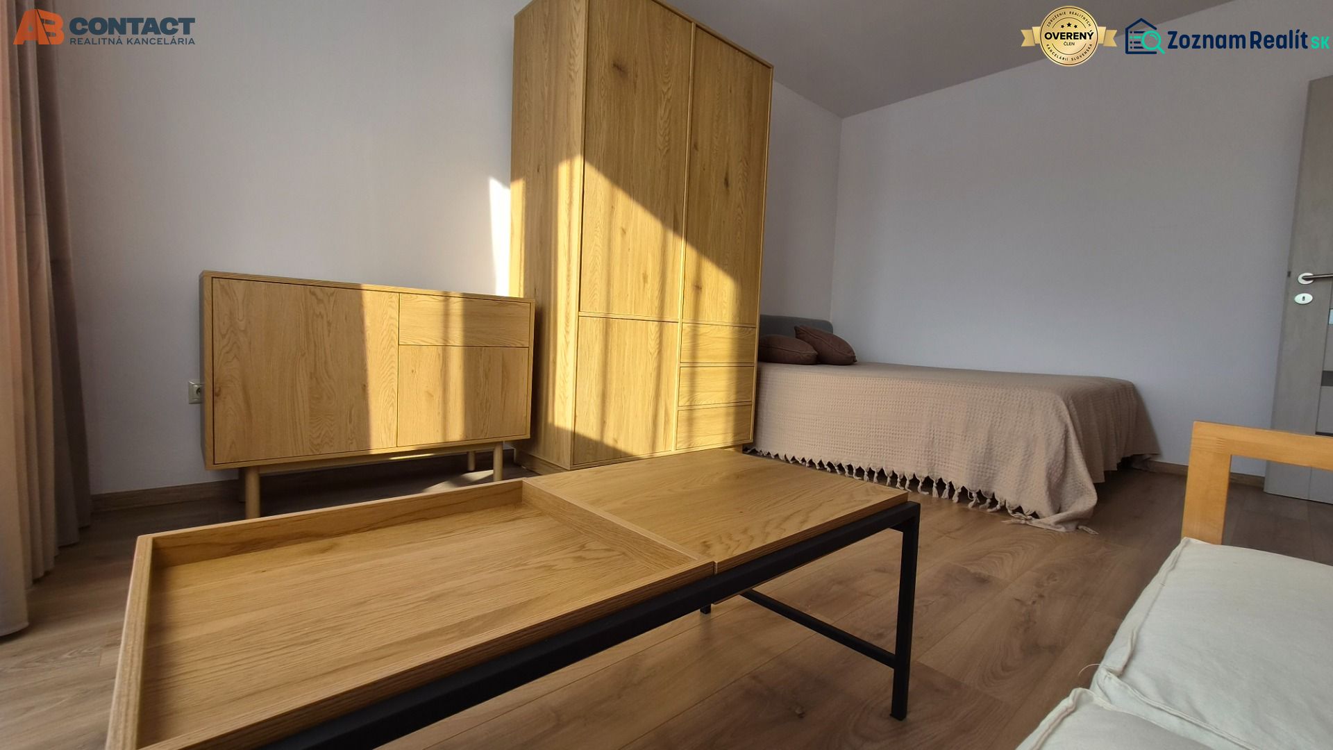 Innenraum einer Einzimmerwohnung mit Bett, Holzmöbeln und Boden mit Holzdekor.