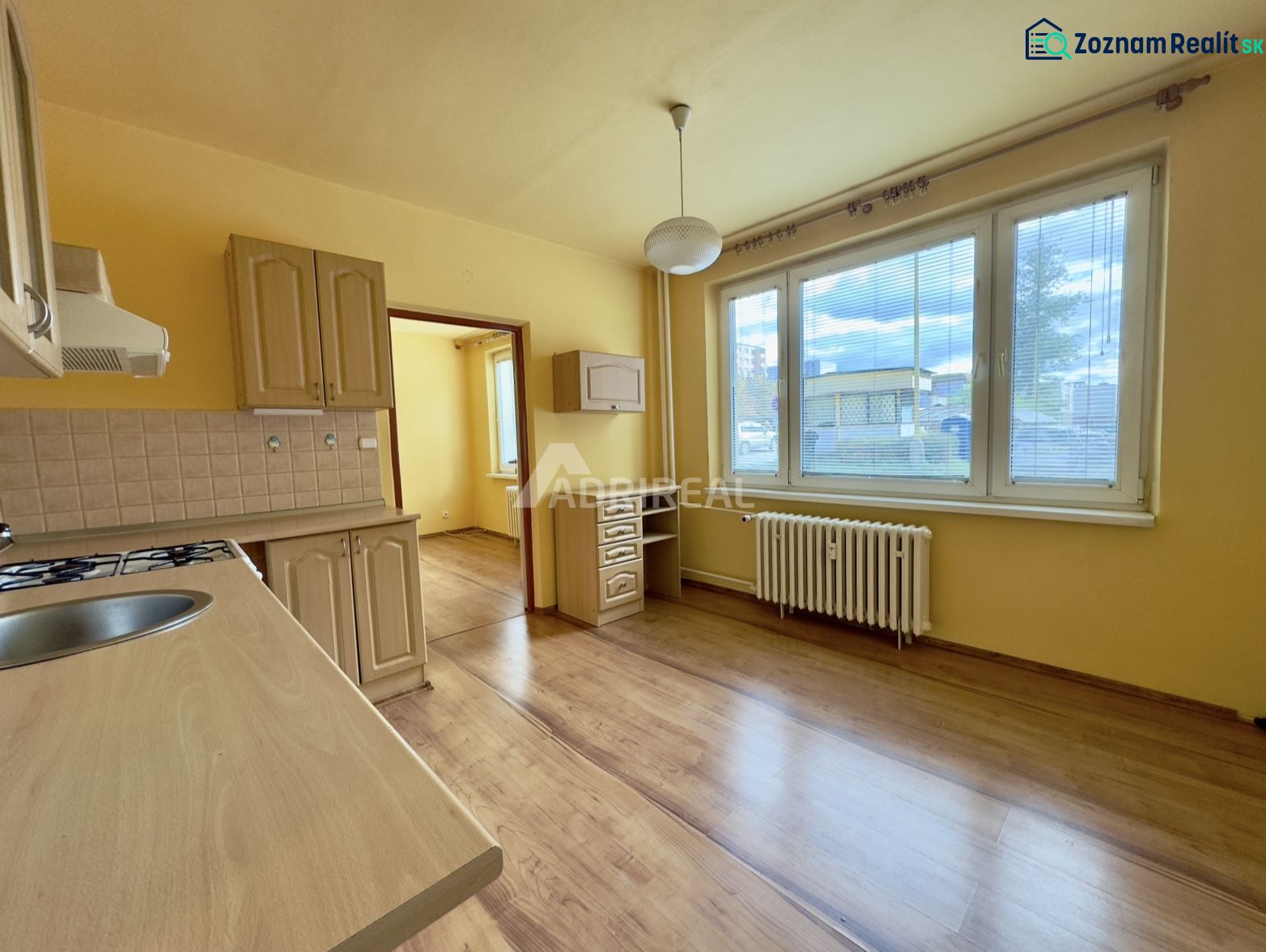 Küche mit Holzboden, Küchenzeile und großem Fenster in einer Einzimmerwohnung.