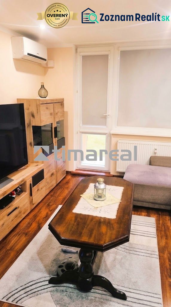 Wohnzimmer in einer 3-Zimmer-Wohnung mit Holzboden, Sofa und Fernseher.