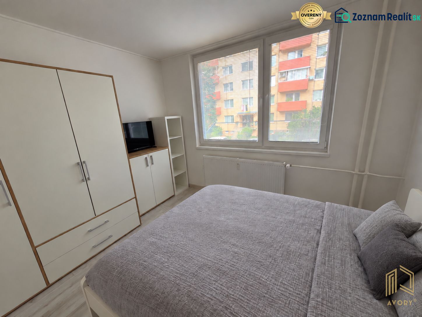 Helles Schlafzimmer in einer 2-Zimmer-Wohnung mit großem Bett, weißem Kleiderschrank und Fernseher.