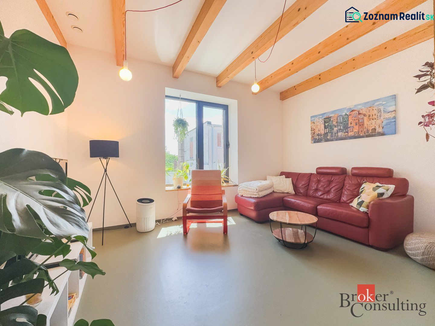 Wohnzimmer in einer 3-Zimmer-Wohnung mit rotem Sofa, Pflanzen und Holzbalken an der Decke.
