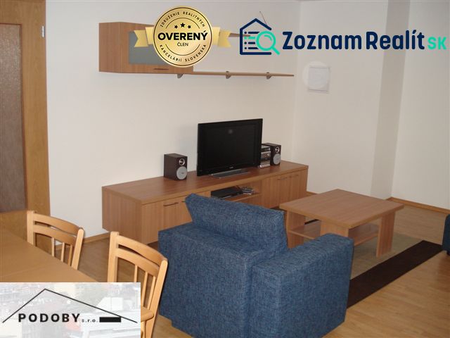 Wohnzimmer mit Holzboden, blauem Sofa und Fernseher in einer 3-Zimmer-Wohnung.