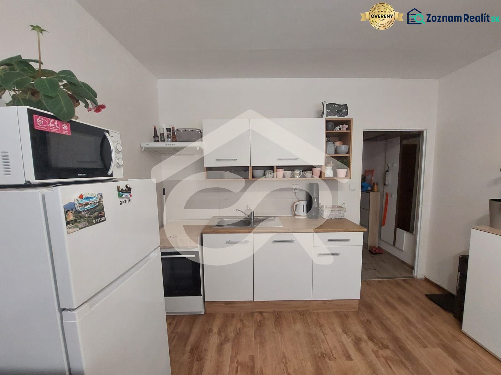Küche in einem Einzimmerapartment mit Mikrowelle, Kühlschrank und Holzboden.