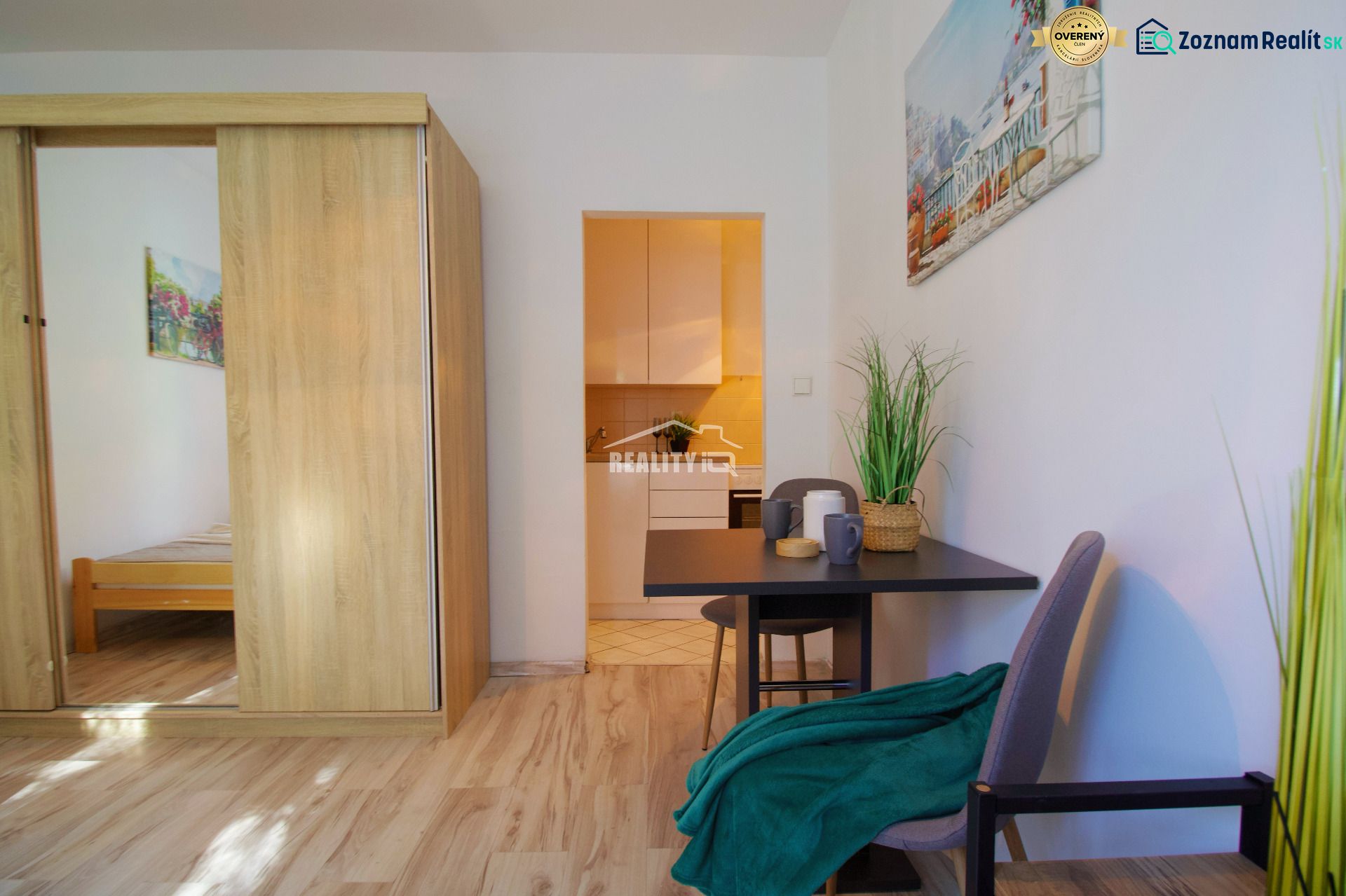 Einzimmerwohnung mit Holzboden, Tisch und Pflanze, gemütliche Einrichtung.