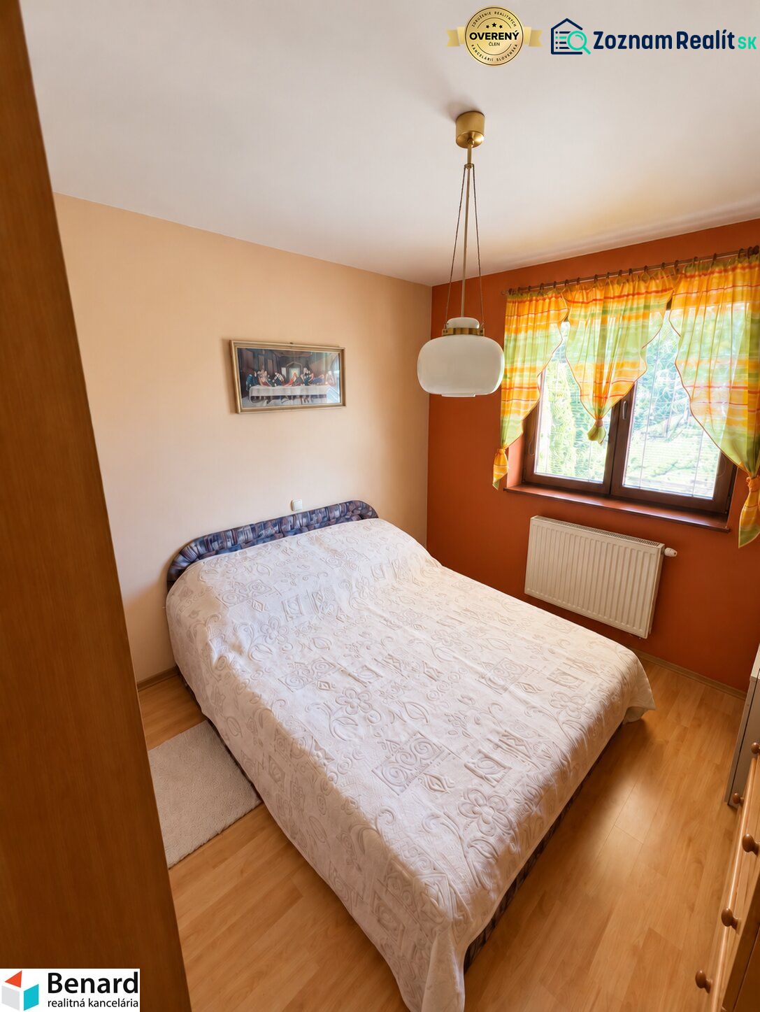 Schlafzimmer in einem Einfamilienhaus mit Bett, Vorhängen und Bodenbelag in Holzoptik.