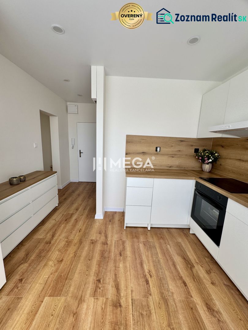 Küche in einer Einzimmerwohnung mit weißen Schränken und einem Boden in Holzoptik.