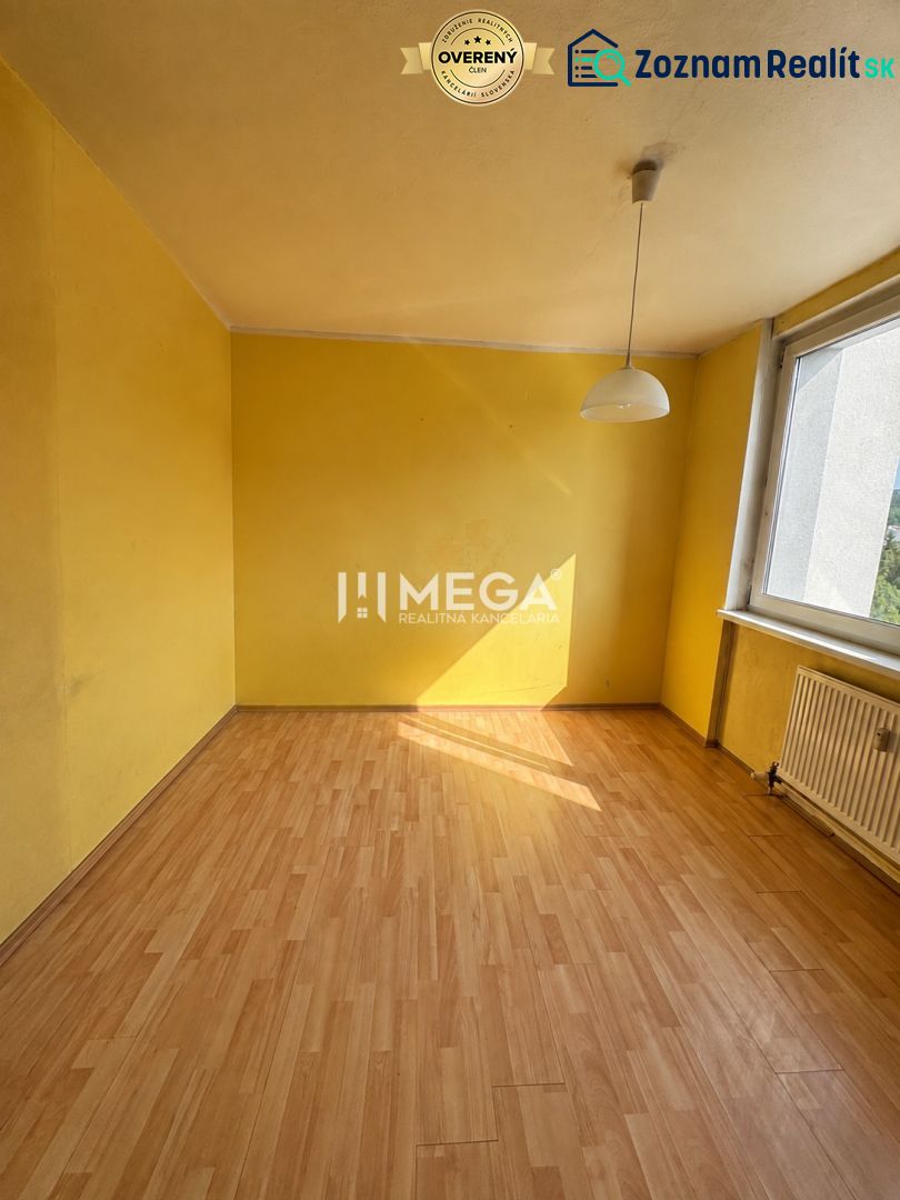 Gelbes Zimmer mit großem Fenster und Holzboden in einer 3-Zimmer-Wohnung.