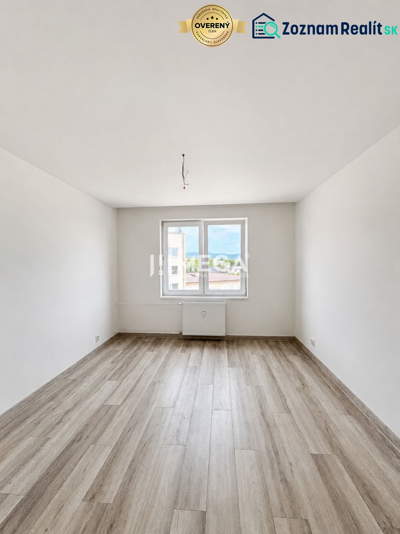 Ein heller, leerer Raum mit weißen Wänden und einem Boden in Holzoptik in einer 2-Zimmer-Wohnung.