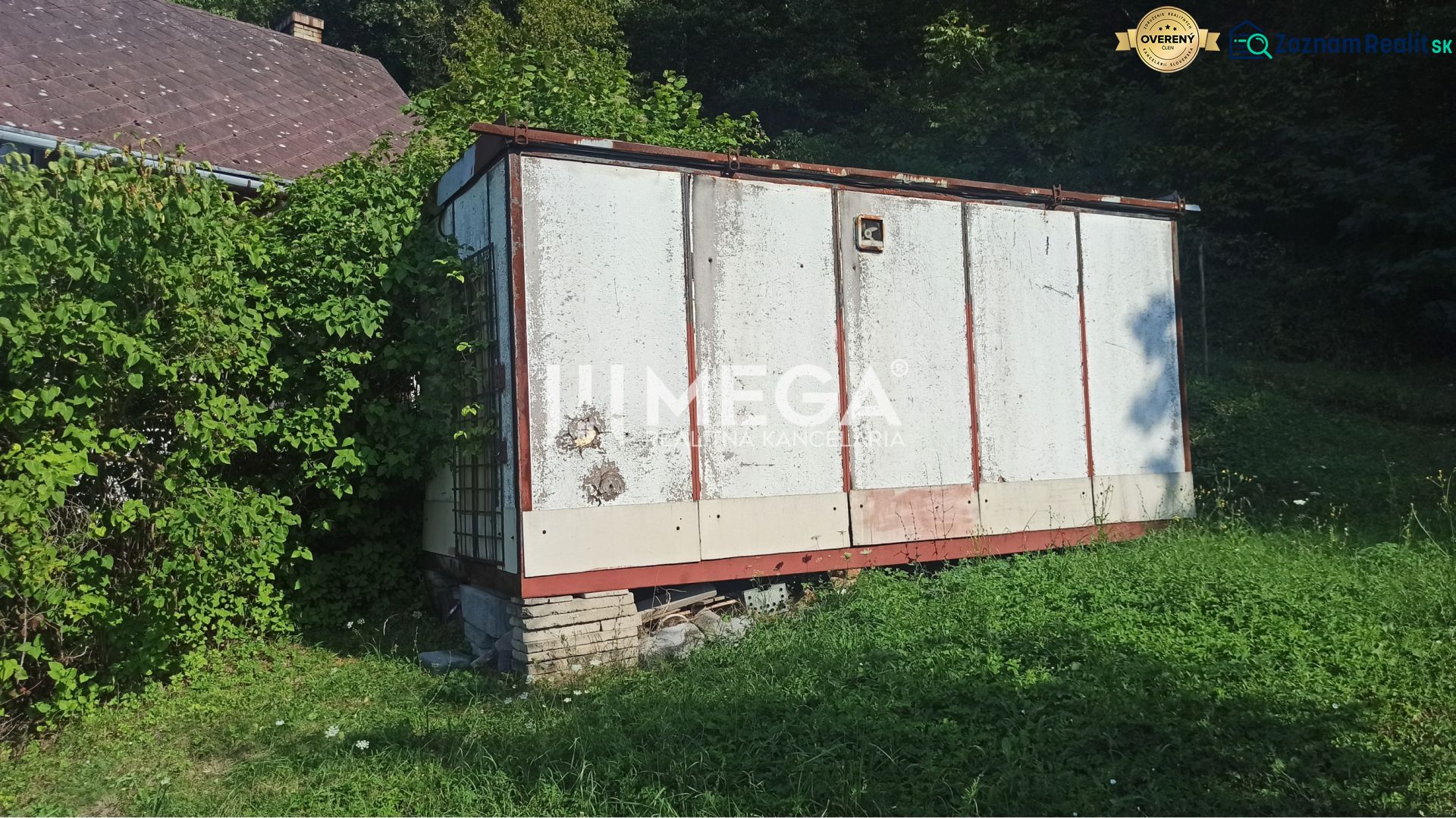Ein älteres Lagerhaus im Garten der Straße in Humenné, umgeben von Grün und wachsendem Gras.