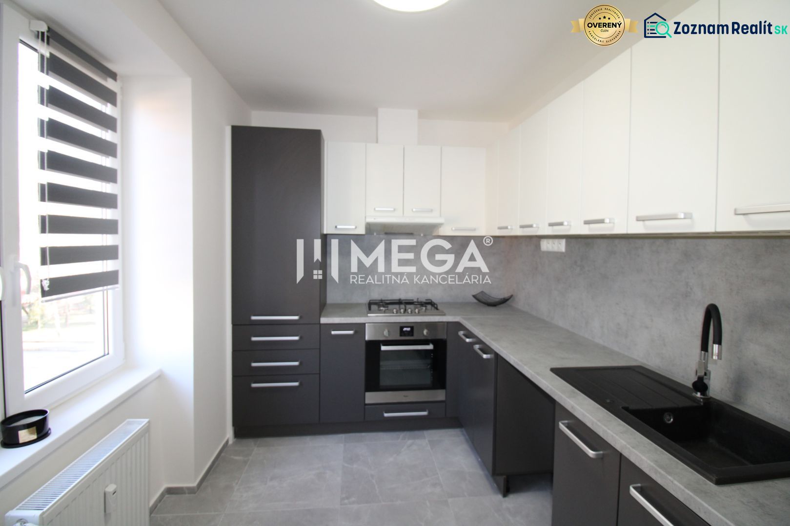 Küche in einer 2-Zimmer-Wohnung mit einfachen Schränken und grauer Arbeitsplatte.