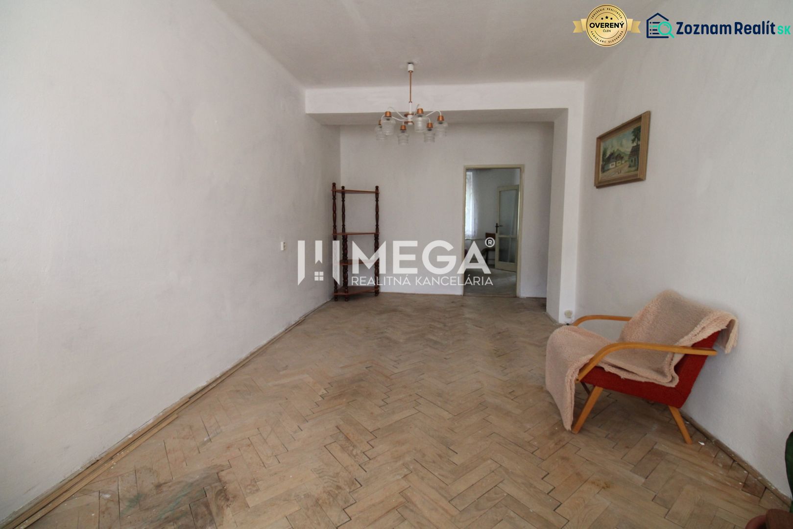 Wohnzimmer mit einem alten Sessel und einem Boden mit Holzdekor in einer 2-Zimmer-Wohnung.