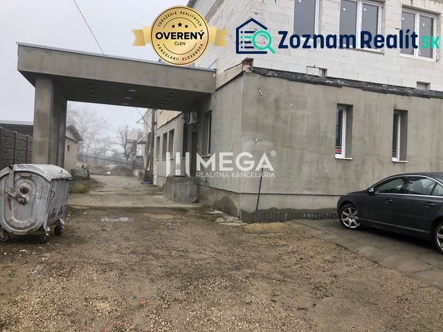 Ein Gebäude in der SNP-Straße in Snina mit einem geparkten Auto und einem Container auf einer Kiesfläche.