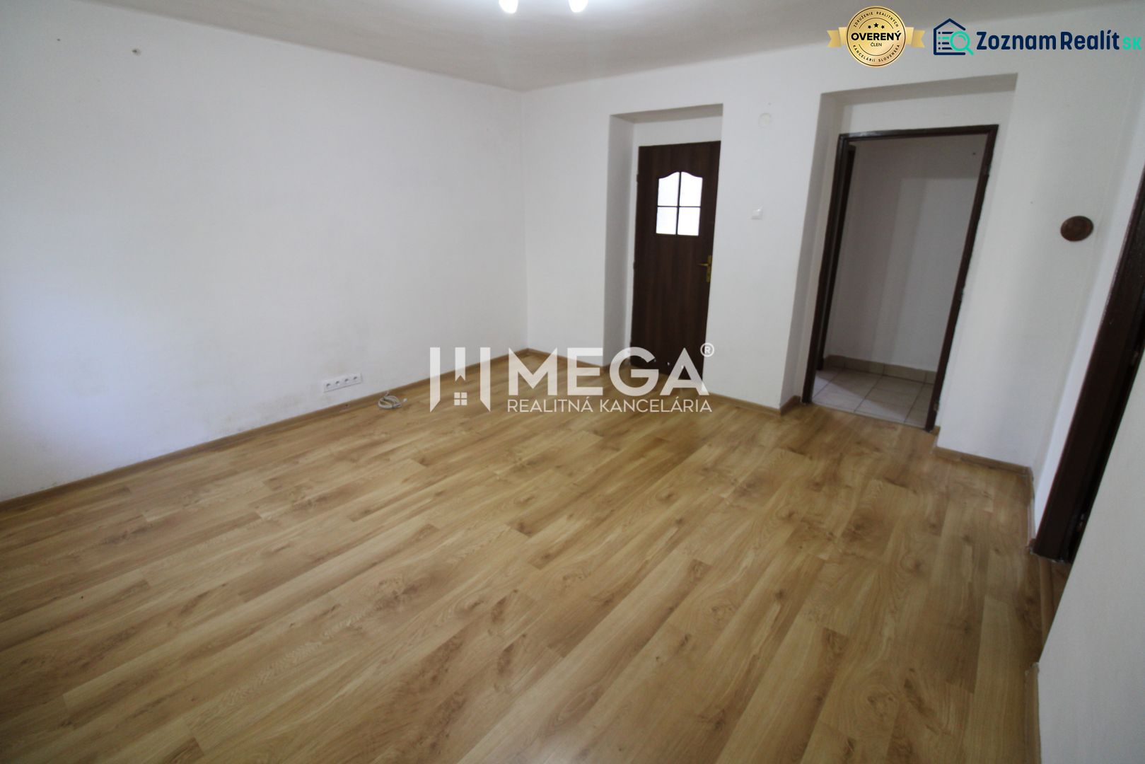 Ein Zimmer in einer 3-Zimmer-Wohnung mit einem Boden in Holzoptik und weißen Wänden.