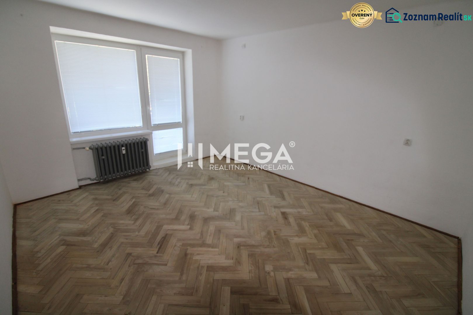 Ein geräumiges Zimmer in einer 2-Zimmer-Wohnung mit einem Boden in Holzoptik und einem Heizkörper.