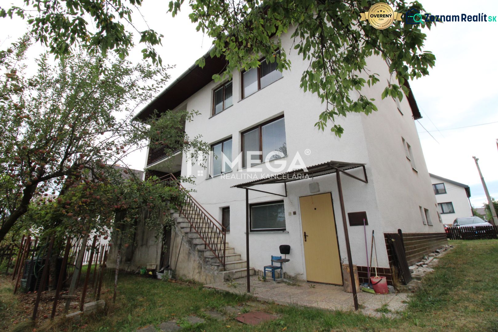 Ein Einfamilienhaus in der Straße in Snina mit zwei Etagen, Bäumen und einer Außentreppe.