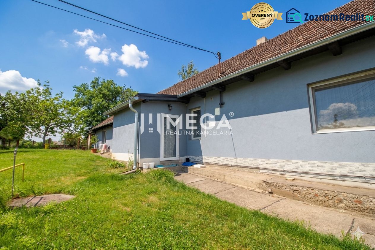 Ein Einfamilienhaus in Veľká Ida mit blauer Fassade, Garten und befestigtem Gehweg.