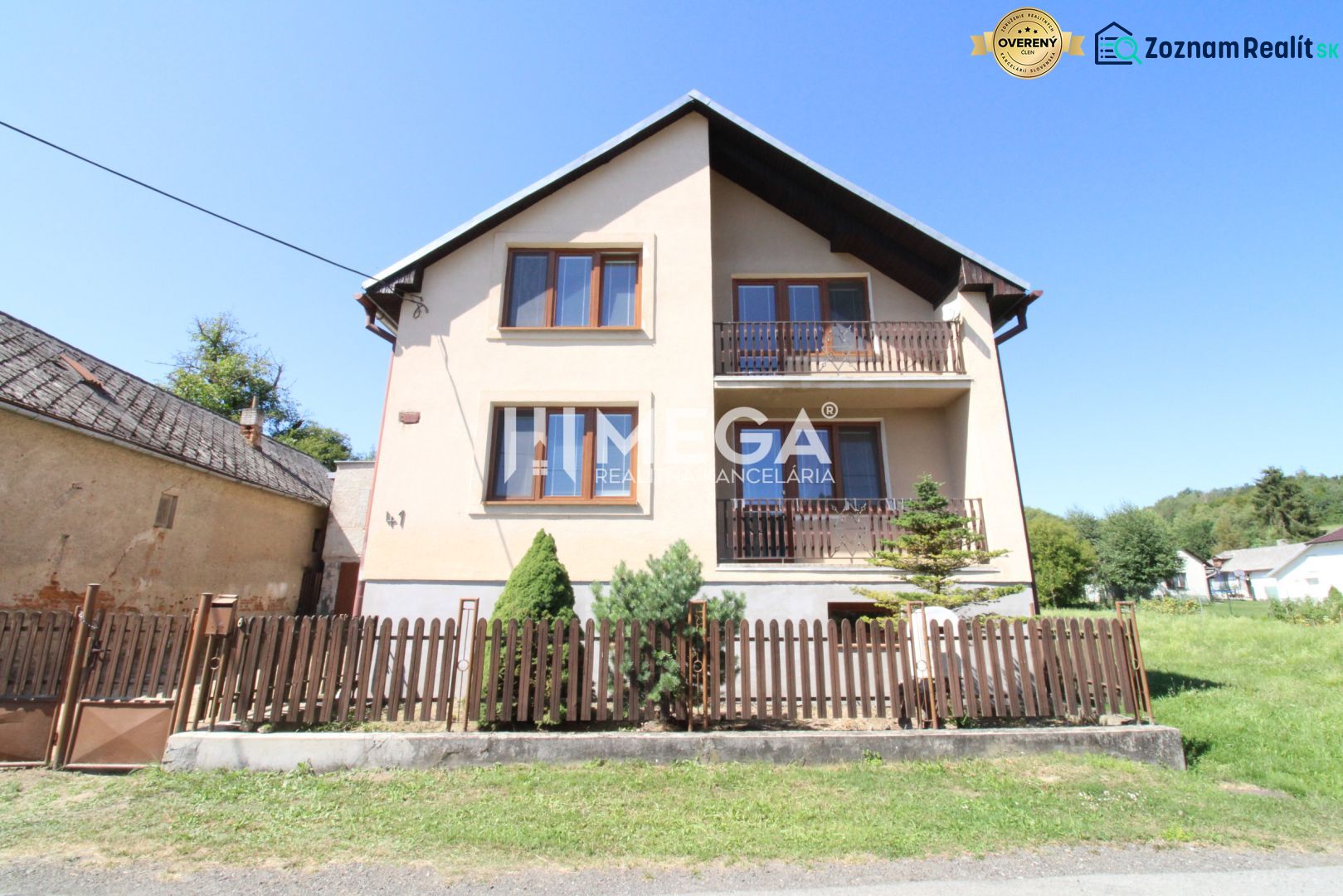 Ein Einfamilienhaus in Nižné Ladičkovce mit zwei Balkonen und einem Holzzaun.