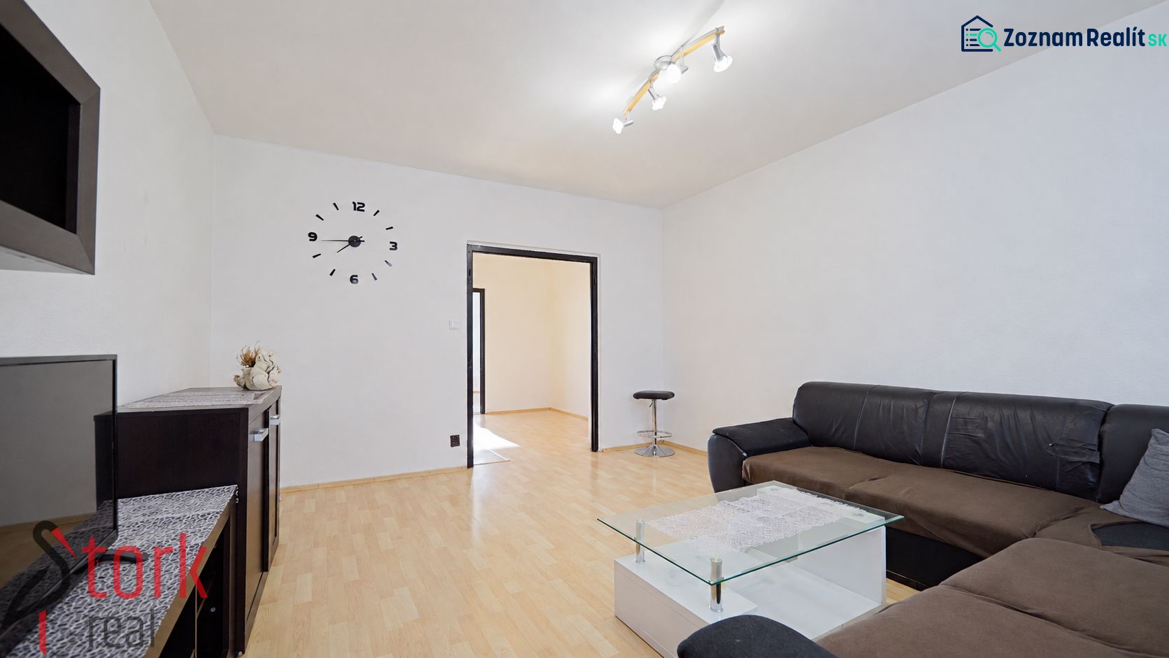 Wohnzimmer in einer 3-Zimmer-Wohnung mit Sofa, Glastisch und Holzboden.