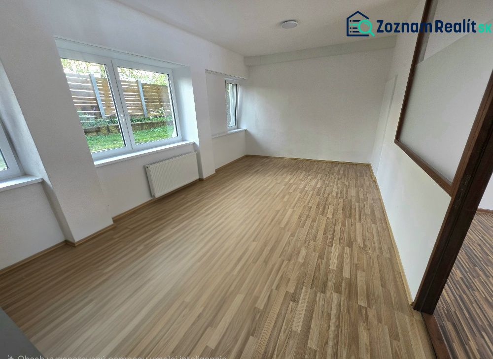 Ein Zimmer mit großen Fenstern und einem Holzboden in einer Zweizimmerwohnung.