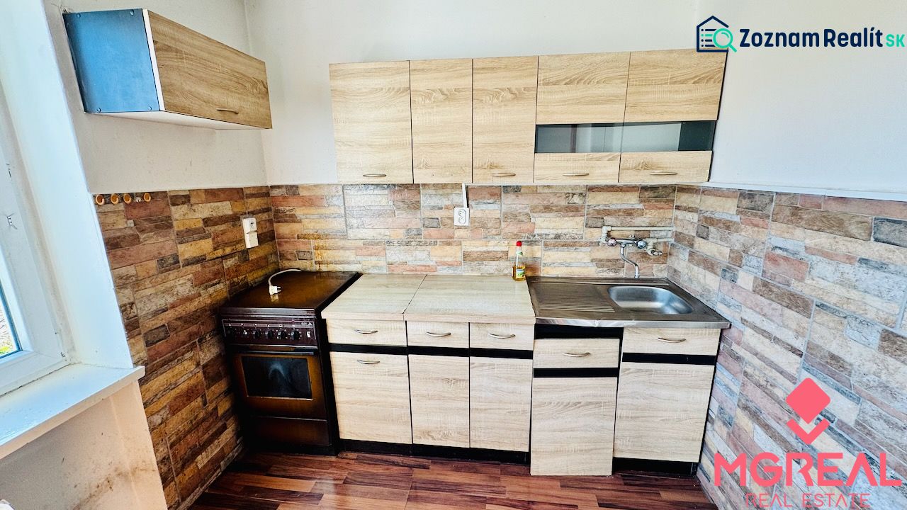 Küche in einer Einzimmerwohnung mit Holzelementen und Steinwandverkleidung.