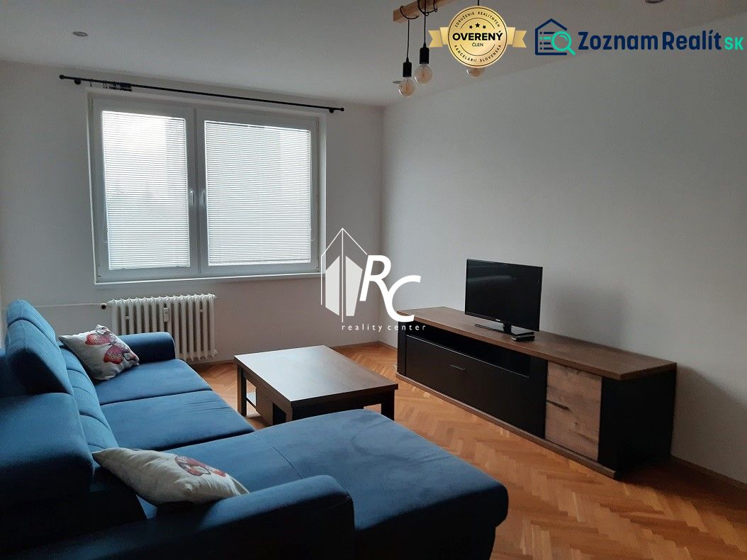 Wohnzimmer in einer Zweizimmerwohnung mit Ecksofa und Holzboden.