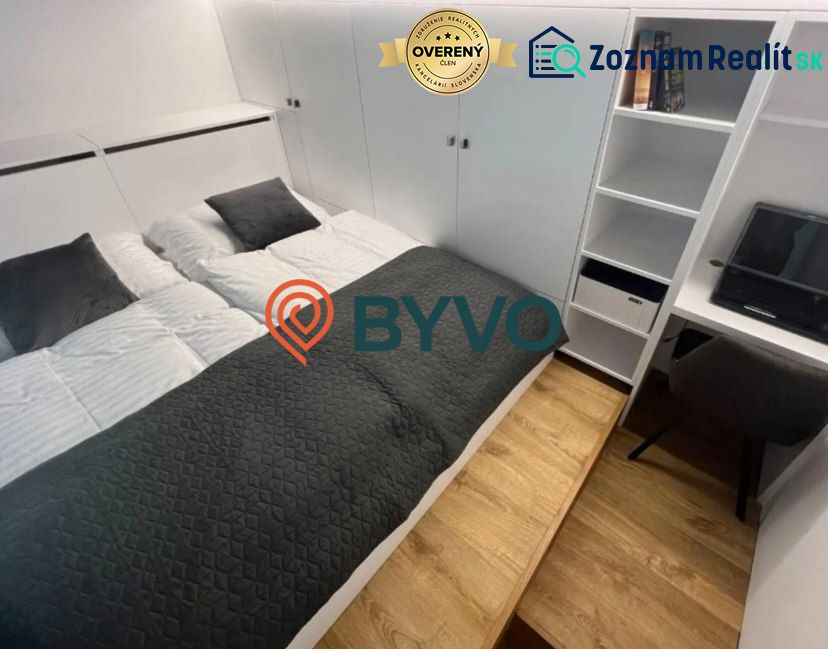 Schlafzimmer in einer Einzimmerwohnung mit Doppelbett und Stauraum, Boden mit Holzdekor.