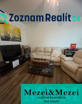 Wohnzimmer einer Zweizimmerwohnung mit Holzboden und bequemen Sitzgelegenheiten.