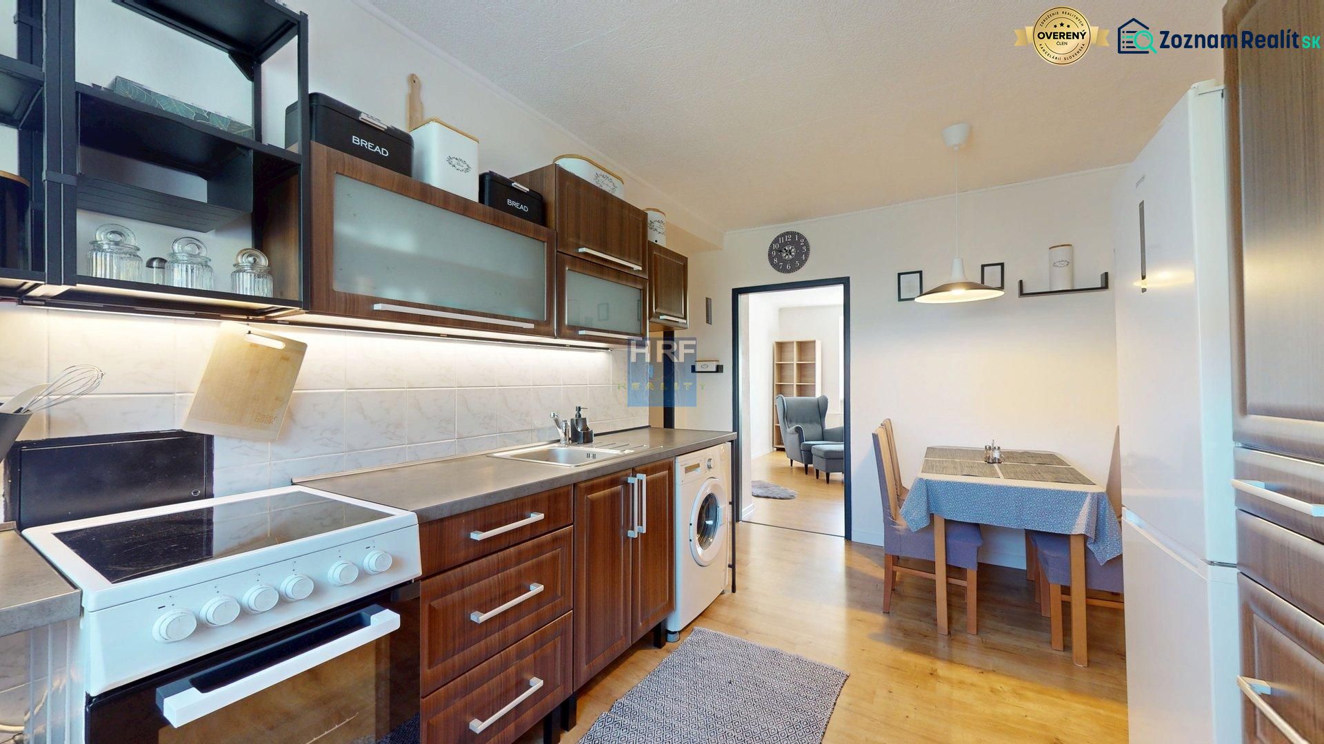 Küche in einer 2-Zimmer-Wohnung mit Herd, Holzboden-Dekor und Esstisch.