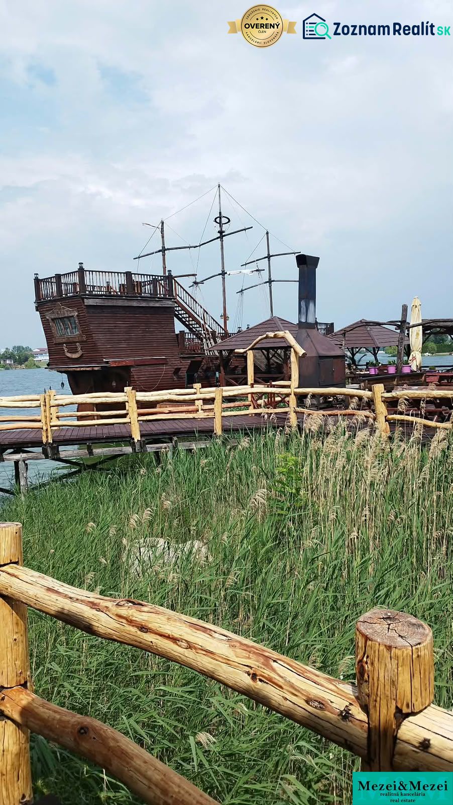 Ein Holzboot als Attraktion bei der Hütte an den Seen von Senec, hinter einem Holzzaun.