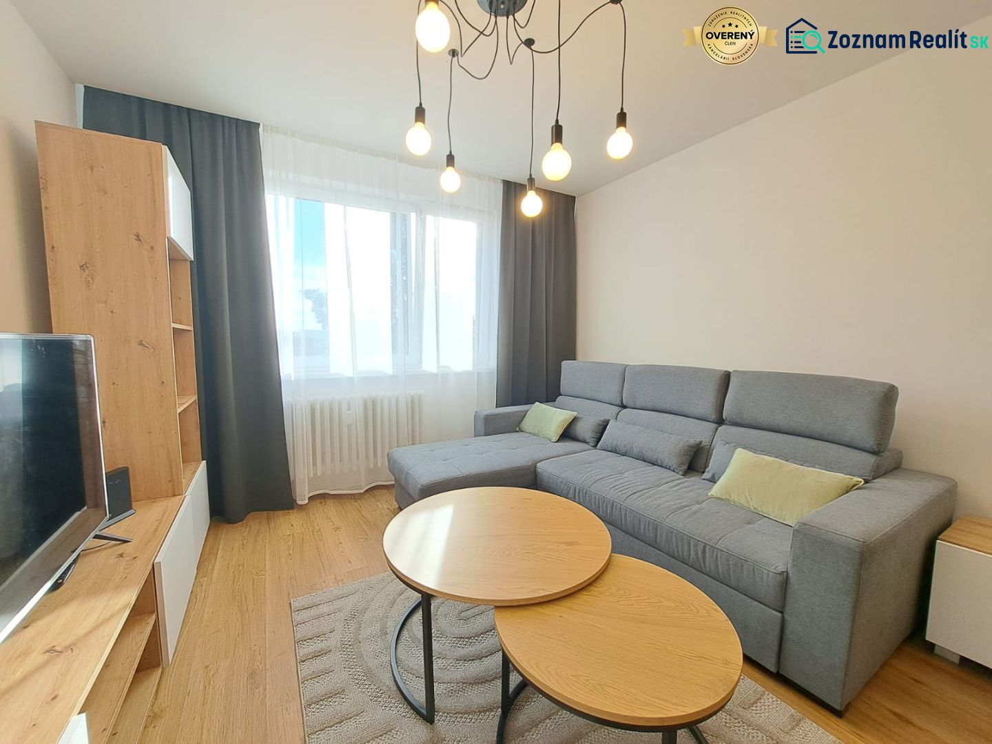 Helles Wohnzimmer in einer Zweizimmerwohnung mit einem bequemen Sofa und einem Boden in Holzoptik.