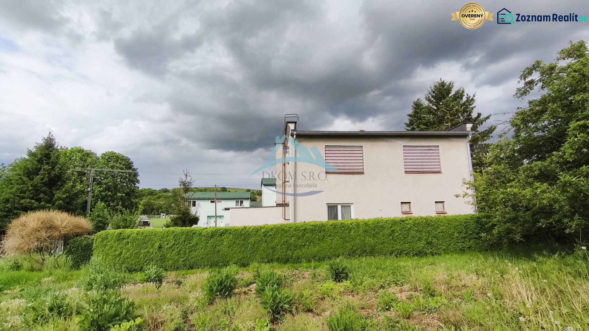 Ein Einfamilienhaus in Nenince, umgeben von dichtem Grün und Bäumen unter einem bewölkten Himmel.