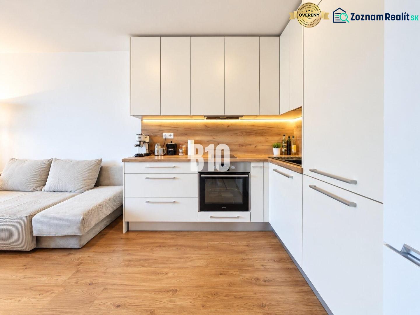 Küche in einer 2-Zimmer-Wohnung mit Holzboden und weißen Schränken.