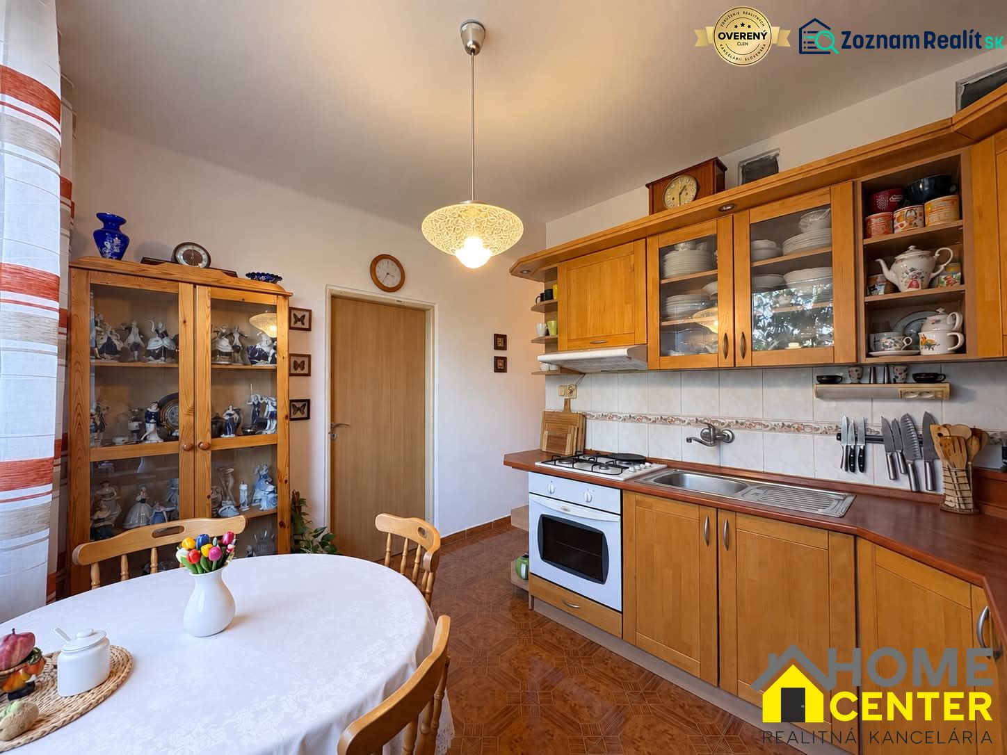 Küche in einer 3-Zimmer-Wohnung mit Holzelementen, Tellern und einer Vase mit Blumen.