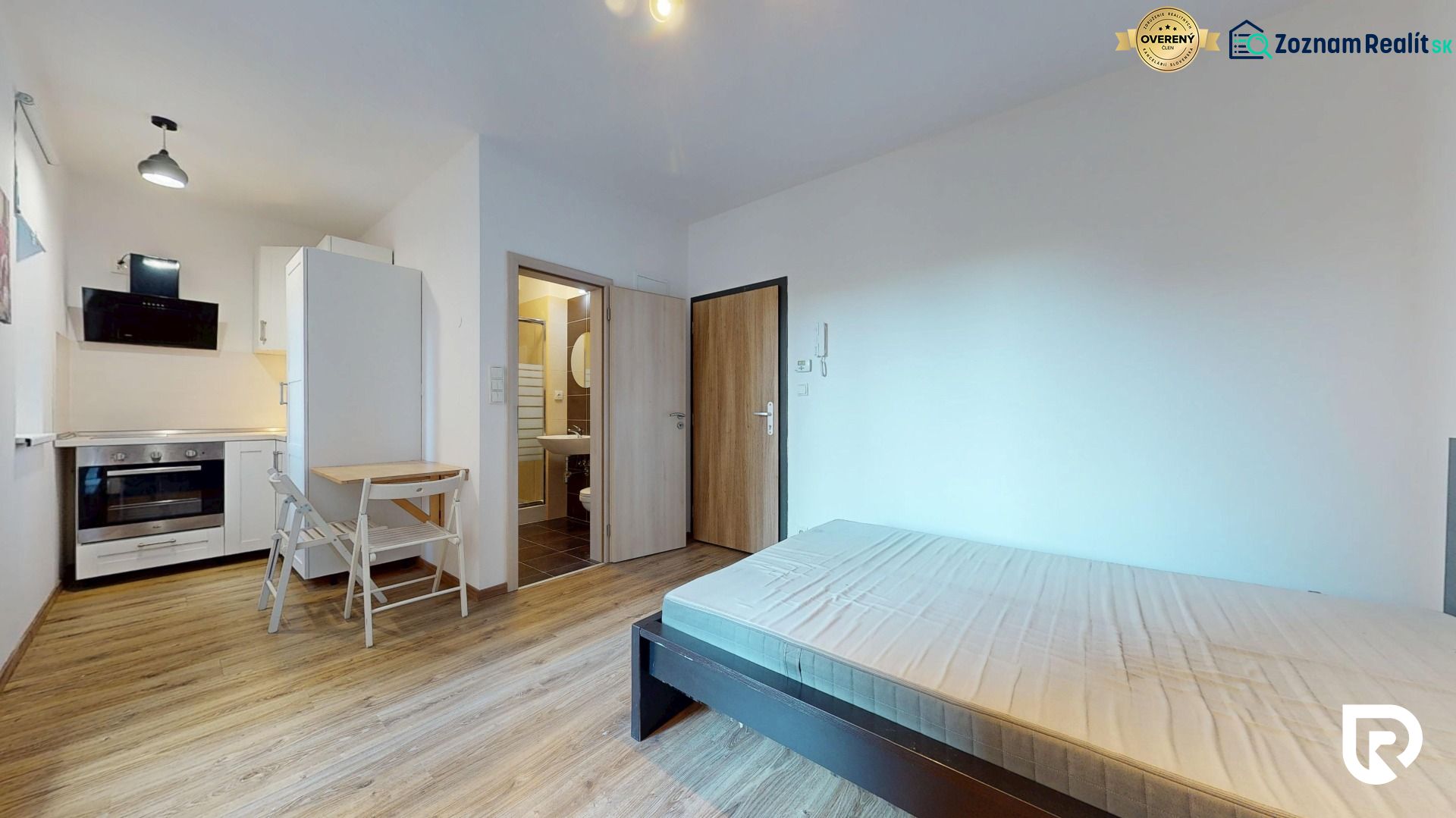 Einzimmerwohnung mit Holzboden, Kochnische, Bett und Badezimmer mit Dusche.