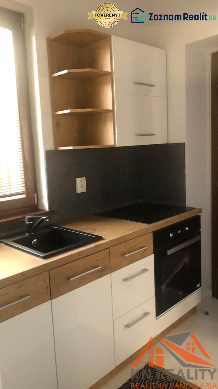 Küchenzeile in einer 2-Zimmer-Wohnung mit schwarzem Spülbecken und weißen Schränken.