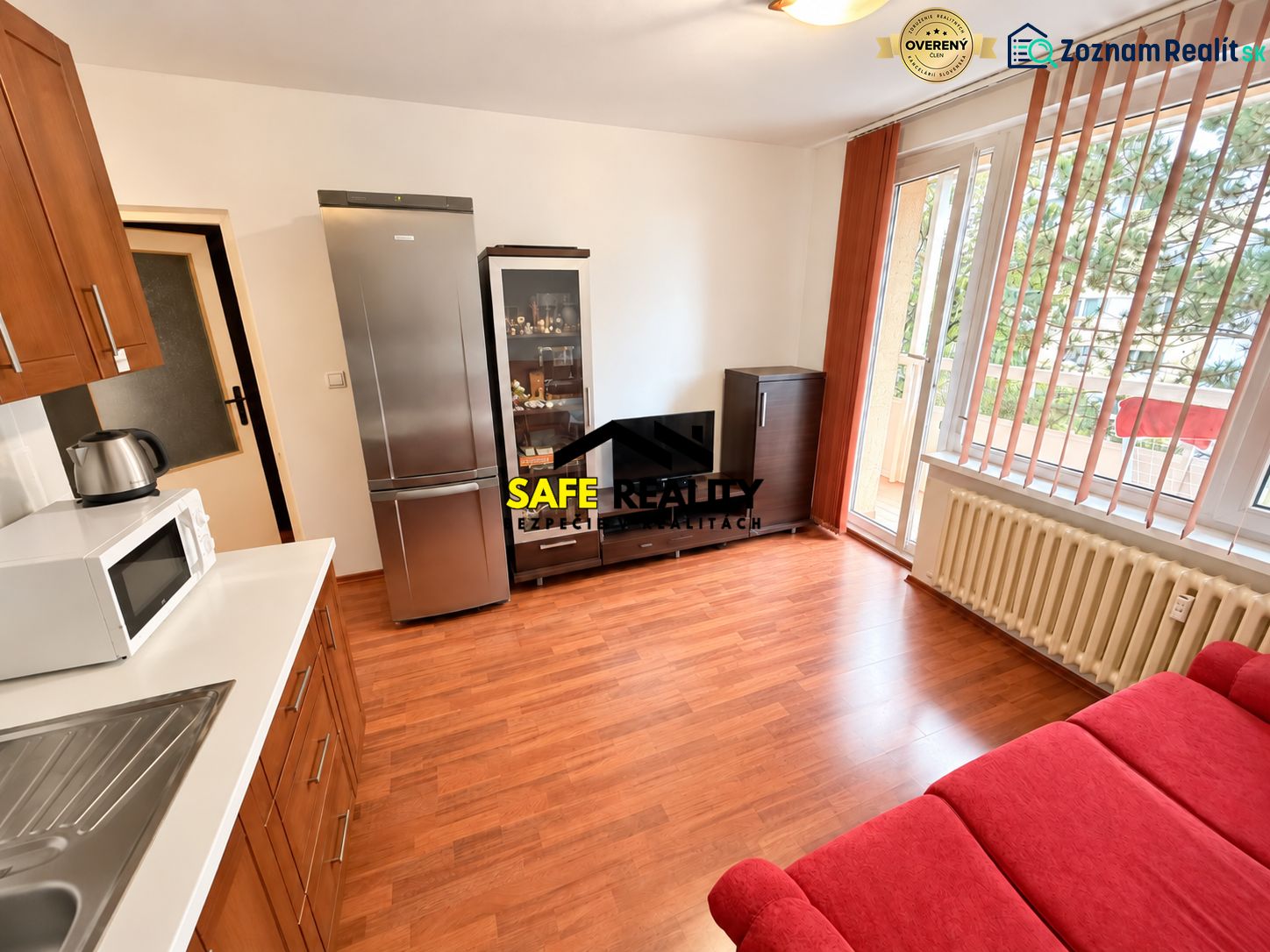 Wohnbereich einer Einzimmerwohnung mit Holzboden und Zugang zum Balkon.