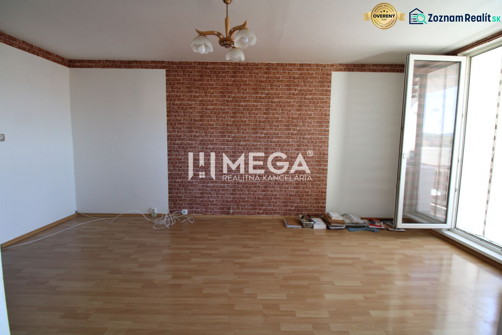 Ein Zimmer mit Ziegelverkleidung, einem Holzboden und einem großen Fenster in einer 3-Zimmer-Wohnung.