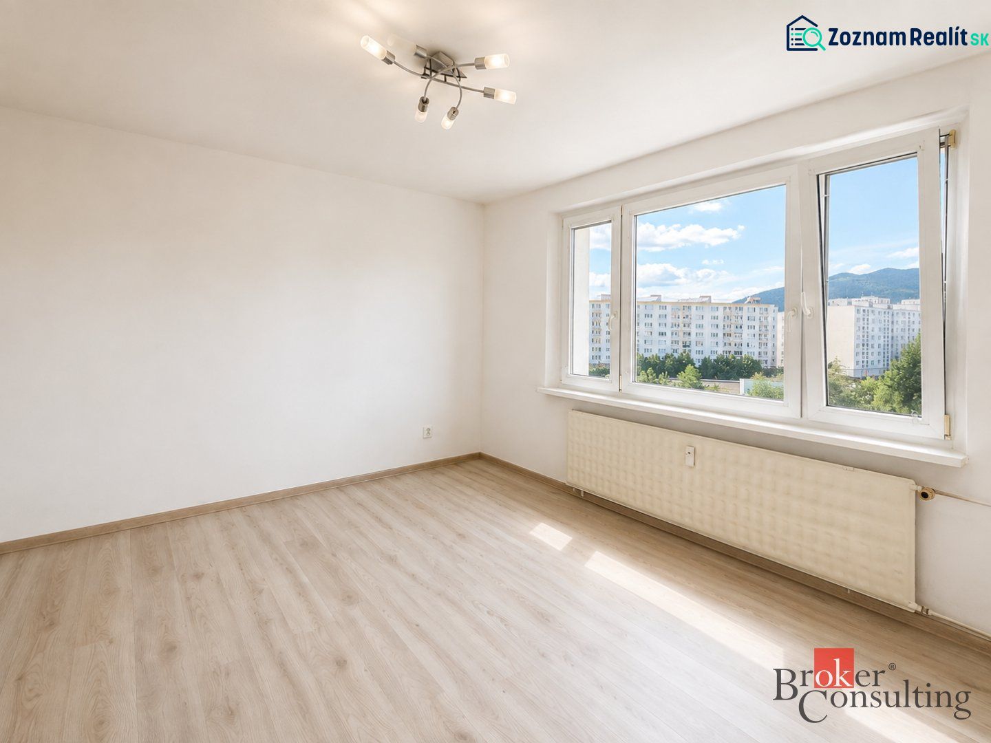 Ein Zimmer mit großen Fenstern und einem Boden in Holzoptik in einer 3-Zimmer-Wohnung.